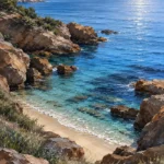 Powder blue and cocoa coastal bedroom wall art print featuring a peaceful coastal cove, smooth rocks, calm waters, and delicate sea grasses for elegant interiors