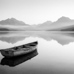 Charcoal and gold black and white photo artwork print featuring a vintage rowboat on a misty mountain lake with reflective water and distant peaks
